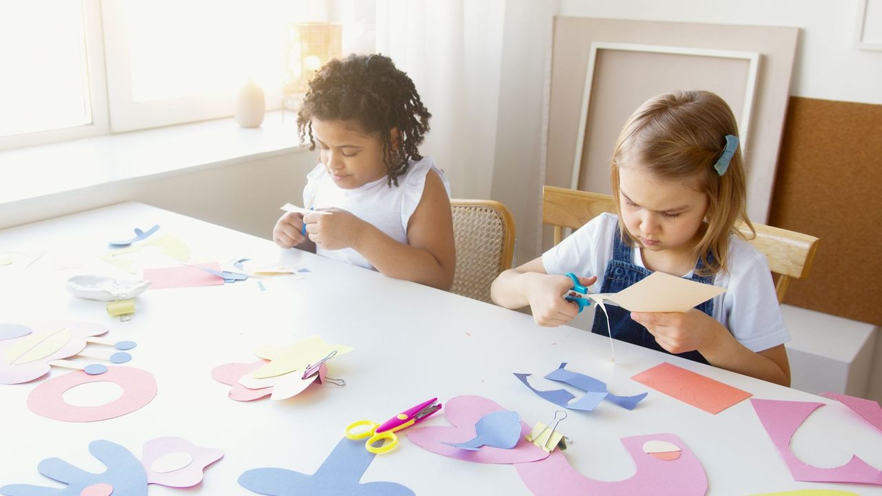 Two young children working side by side at a table during a therapy session