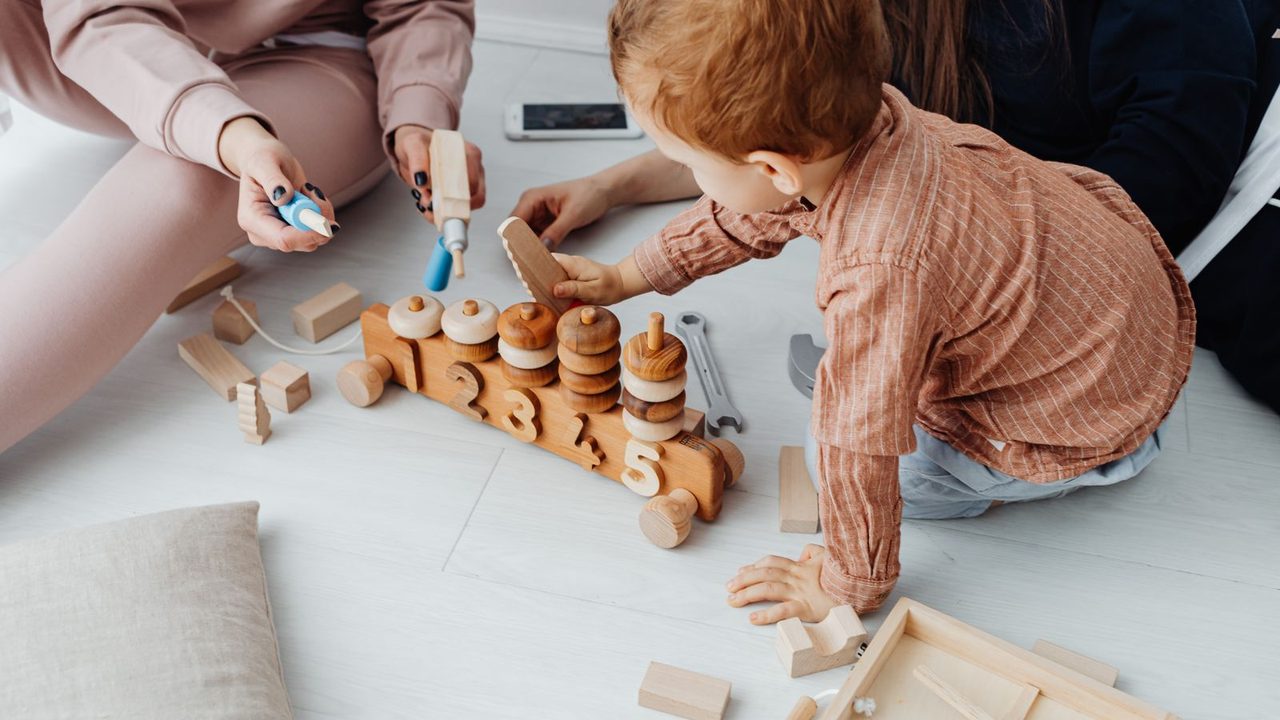 A toddler playing quietly with wooden toys on the floor